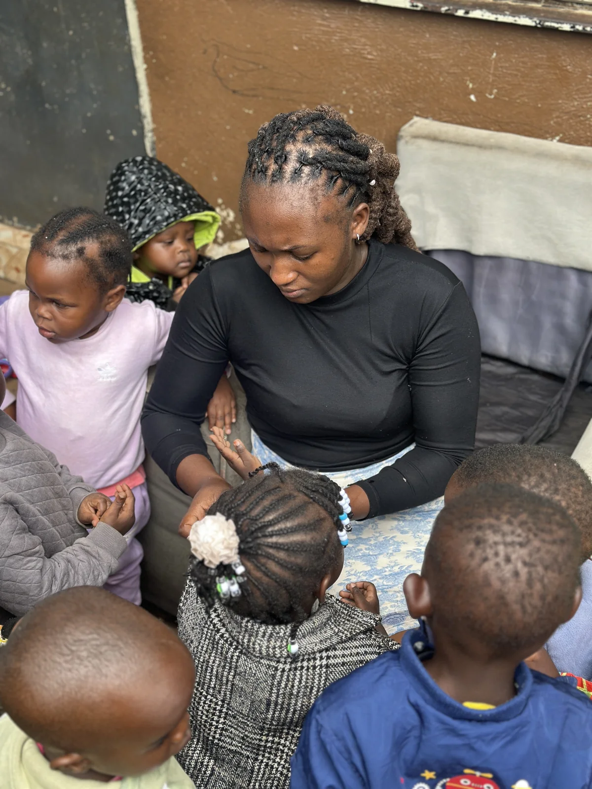 A caregiver surrounded by children during an ordinary day at Little Heaven