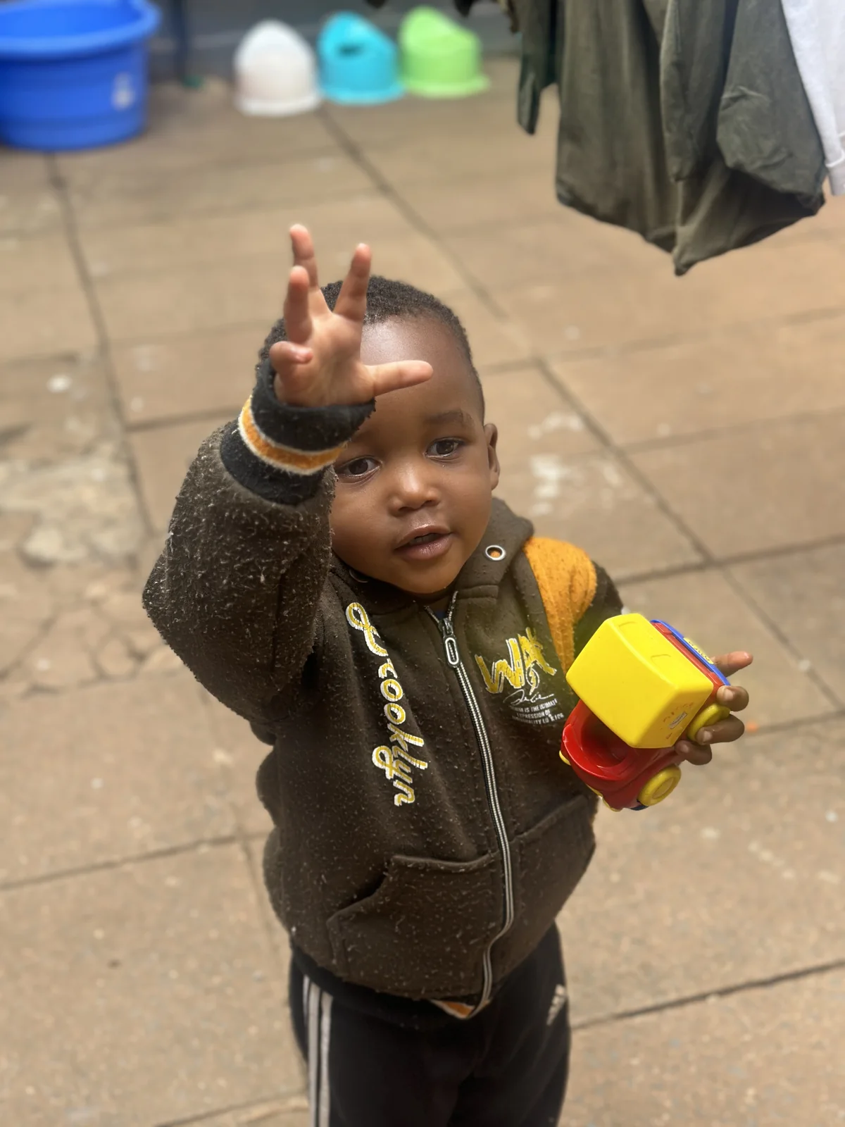 A young child reaching towards the camera outside Little Heaven