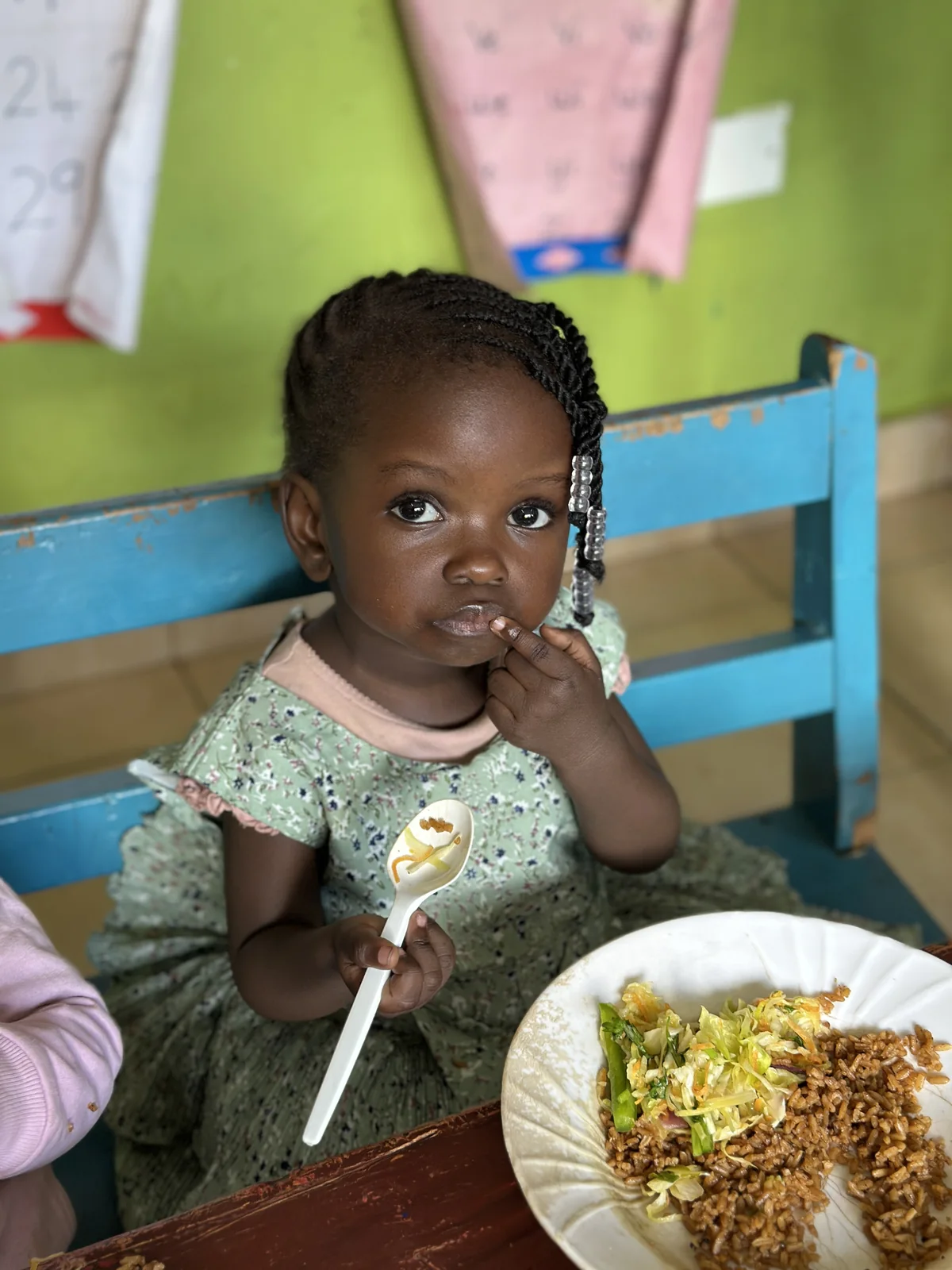 A child seated at a blue chair during snack time