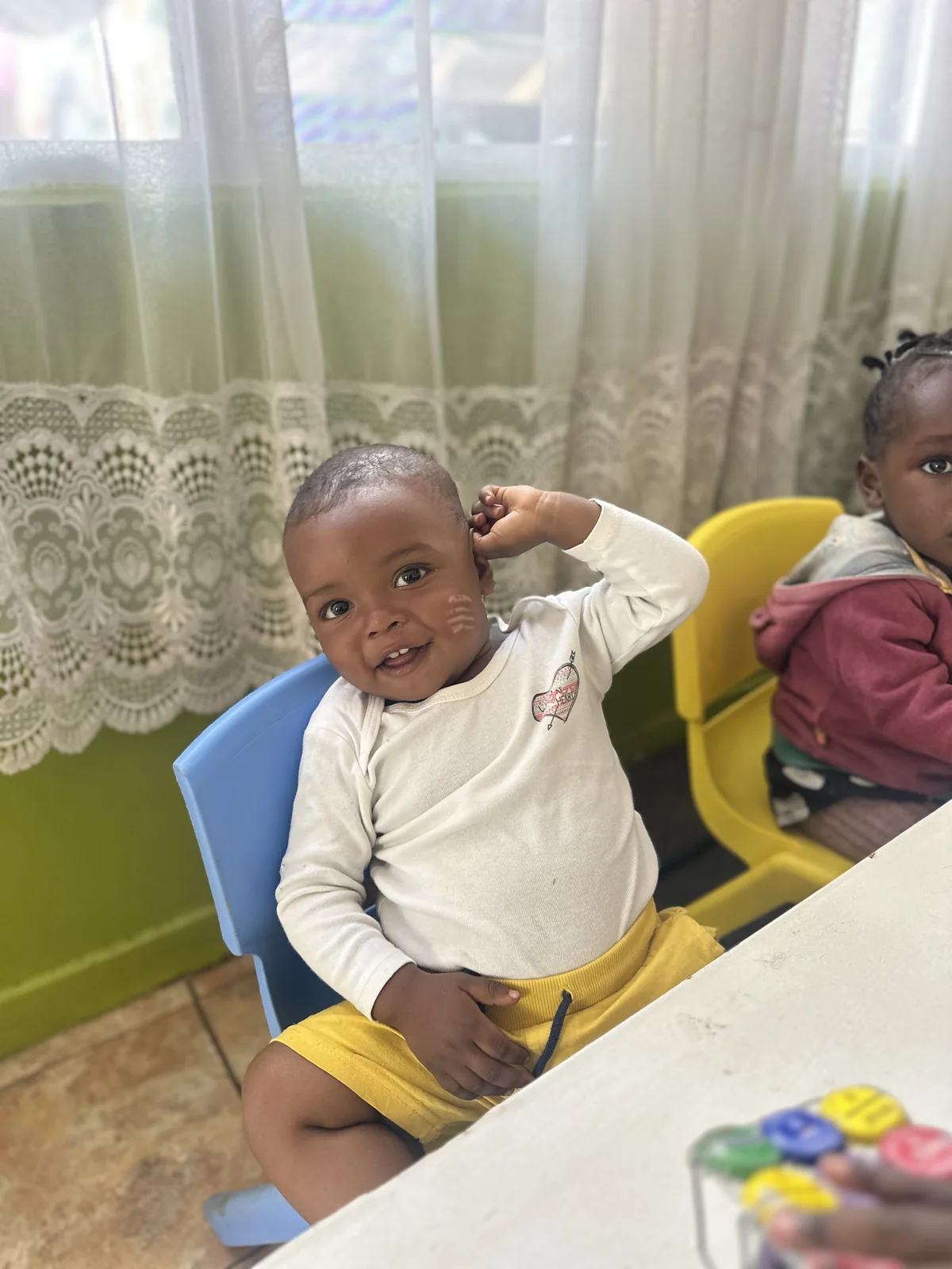 A child smiling from a yellow chair