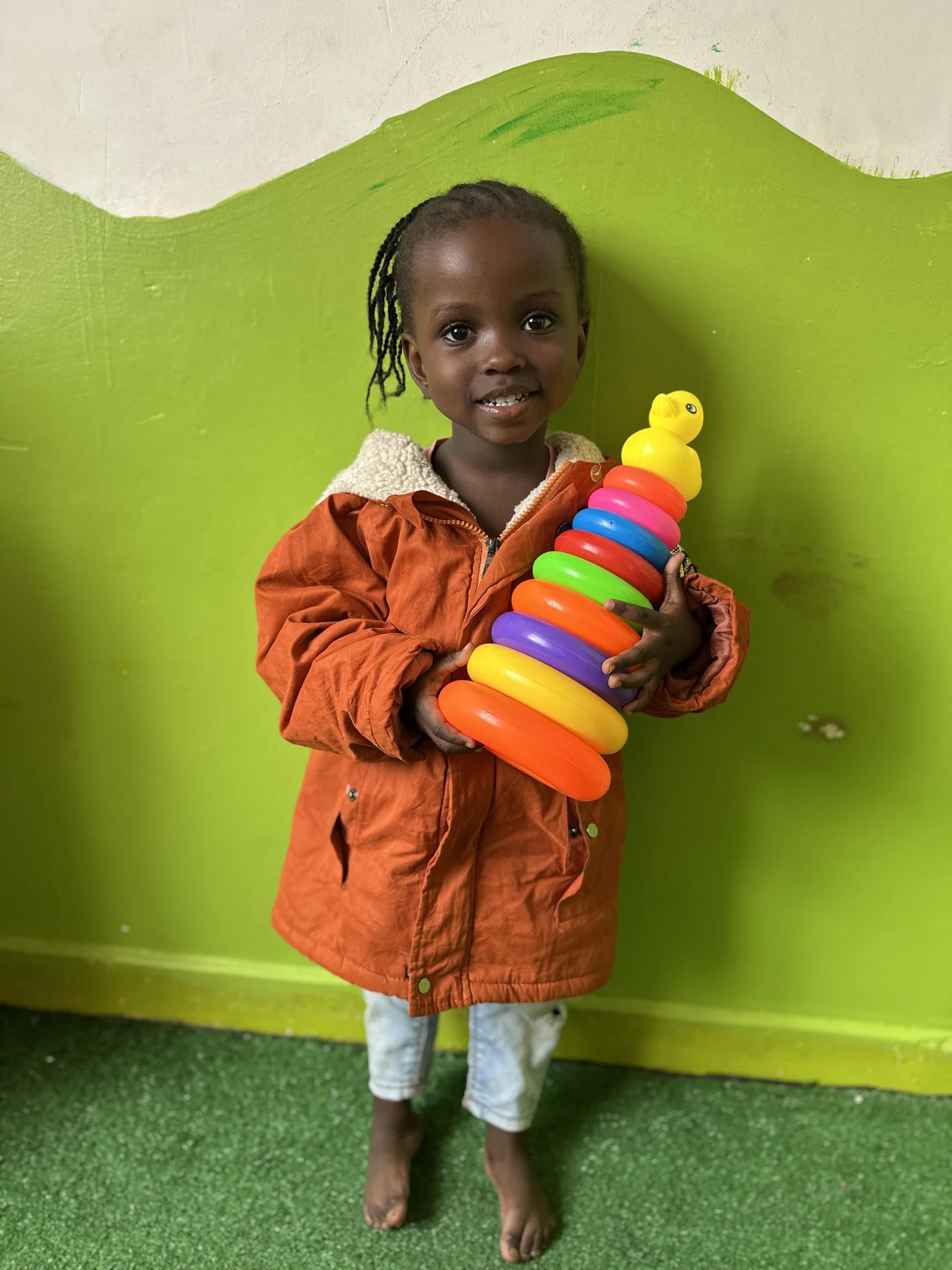 A child proudly holding a colourful stacking-ring toy